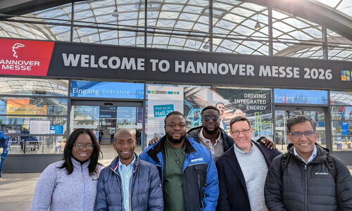 A group of six delegates poses in front of the main entrance of Hannover Messe 2026.