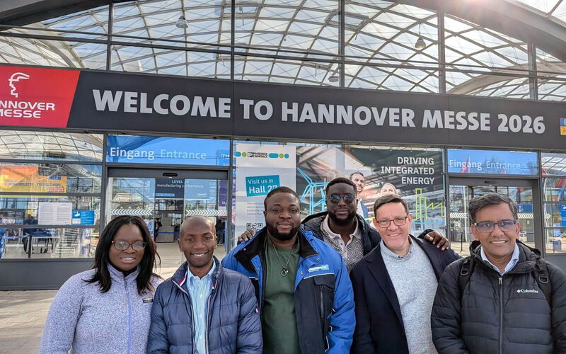 A group of six delegates poses in front of the main entrance of Hannover Messe 2026.