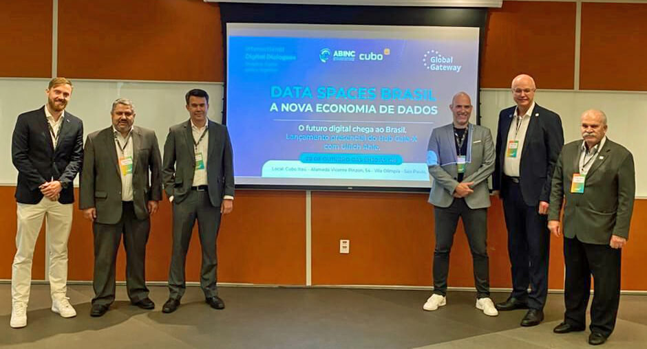 Participants of the launch of the Gaia-X Hub in Brazil, standing beside the presentation screen